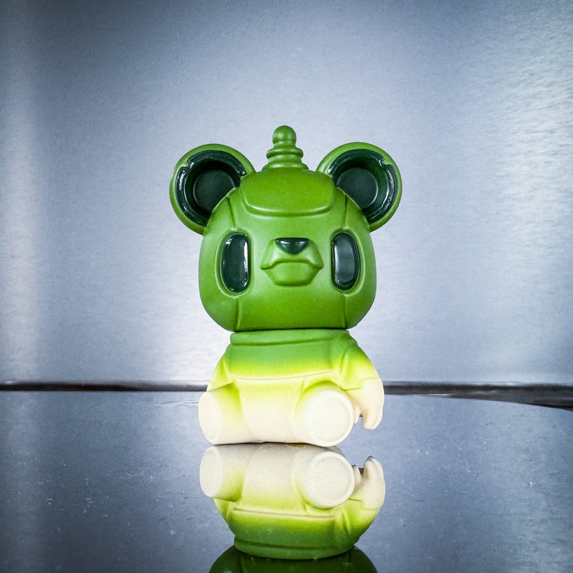 Green and white robot-like figure on a reflective surface with a gray background