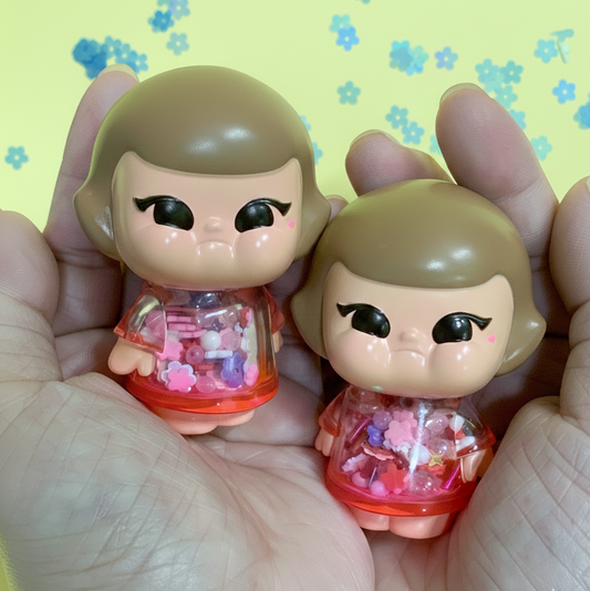 Two small figurines held in hands with a floral patterned background